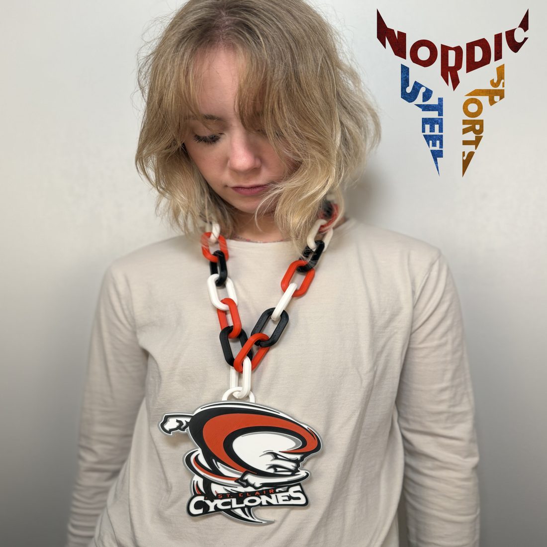 A fan wearing an orange, black and white St. Clair Cyclones hype chain with a large logo medallion